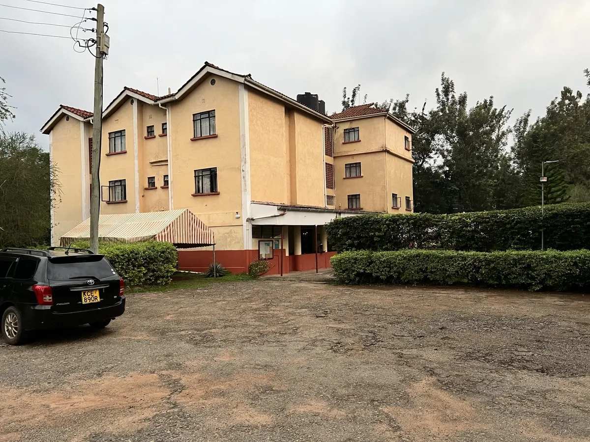Three-storey apartment block with a gravel courtyard and hedges
